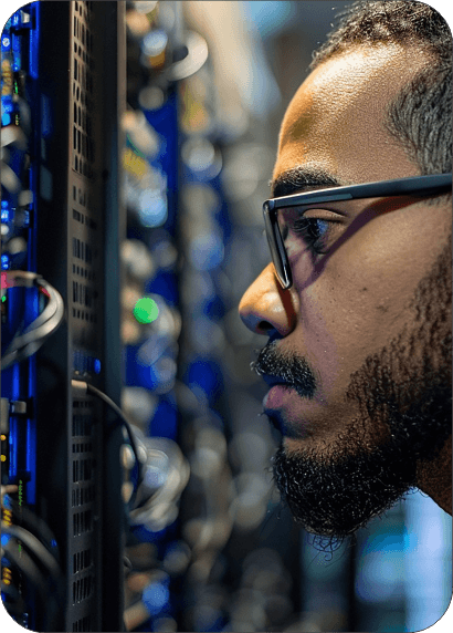 Individual examining server equipment in a data center with a focused expression.
